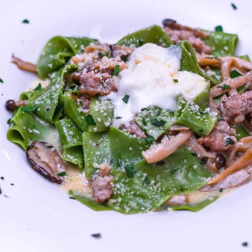 Green pappardelle pasta with sausage, mushrooms, parmesan cheese, and a dollop of cream.